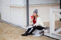 Cheerful fashionable blonde holding coffee outdoors on wooden background at the winter beach enjoyng holidays Royalty Free Stock Photo