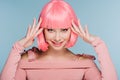 Cheerful fashionable girl gesturing and posing in pink wig isolated