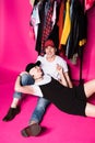 Cheerful fashionable senior couple resting under diferent clothes on hangers