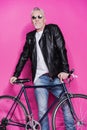 Cheerful fashionable senior man wearing leather jacket and sunglesses standing with bicycle Royalty Free Stock Photo