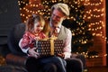 Cheerful fashioned senior man with grey hair and beard with little girl with gift box Royalty Free Stock Photo