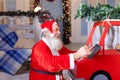 Cheerful Father Christmas preparing gift with tablet.