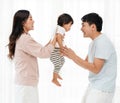 cheerful father and mother lifting and playing with toddler baby on white window background. happy family Royalty Free Stock Photo