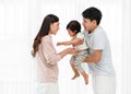 cheerful father and mother lifting and playing with toddler baby on white window background. happy family Royalty Free Stock Photo