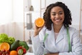 Cheerful female dietician holding fresh orange half Royalty Free Stock Photo