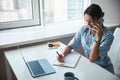 Cheerful female doctor talking on cellphone and making notes Royalty Free Stock Photo