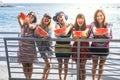 Cheerful female friends have fun and enjoy the summer lifestyle eating a fresh and health red watermelon together in friendship -