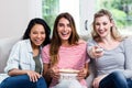 Cheerful female friends with remote and popcorn at home Royalty Free Stock Photo