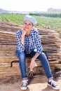 Cheerful female gardener sitting on bundles of bamboo poles