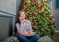 Cheerful female having cellphone conversation, sitting near tree with decoration Royalty Free Stock Photo