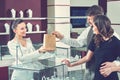 Cheerful female jeweler handing purchase in a shopping bag to he Royalty Free Stock Photo