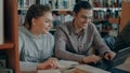 Cheerful female and male college students working on laptop together while sitting at table at university library with Royalty Free Stock Photo