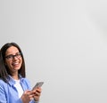 Cheerful female manager wearing smart casual and eyeglasses text messaging over smart phone. Happy young woman scrolling on social Royalty Free Stock Photo