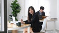 Female office worker smiling to camera and siting with her colleague in office. Royalty Free Stock Photo