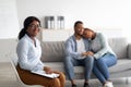 Cheerful female psychologist and young black couple hugging after effective therapy at office, copy space Royalty Free Stock Photo