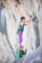 Female rock climber standing on shoulders of her partner in order to start climbing challenging route