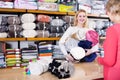 Cheerful female seller demonstrating coverlets to senior buyer in textile shop Royalty Free Stock Photo