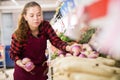 Cheerful female shopping assistant selling purple turnip