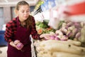 Cheerful female shopping assistant selling purple turnip