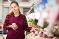 Cheerful female shopping assistant selling purple turnip