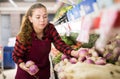 Cheerful female shopping assistant selling purple turnip