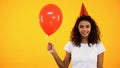 Cheerful female teen holding red balloon and smiling, birthday celebration, fun