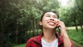A cheerful female tourist talks on her smartphone with a smiling face and relaxes in a nature park. concept of technology and
