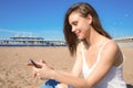 Cheerful female watching video on cell telephone, resting on seashore Royalty Free Stock Photo