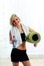 Cheerful fit woman holding a bottle with water and yoga mat Royalty Free Stock Photo