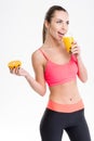 Cheerful fitness girl drinking juice and holding half of orange Royalty Free Stock Photo