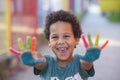 Cheerful five year old boy with hands painted in colorful paints