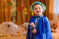 Cheerful five-year-old child in a blue suit and hat dancing on a blurred background of kindergarten
