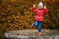 A cheerful five-year-old girl in a pink warm jacket and full-length jeans