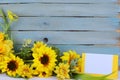 Cheerful floral with bright yellow silk sunflowers and a rustic blue washed plank background with blank card