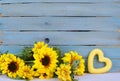 Cheerful floral with bright yellow silk sunflowers and a rustic blue washed plank background