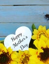 Cheerful floral with bright yellow silk sunflowers and a rustic blue washed plank background for Mother`s Day in May.