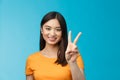 Cheerful friendly asian woman in yellow t-shirt smiling broadly, show number two, twice, win second place, smiling Royalty Free Stock Photo