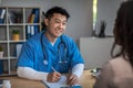 Cheerful friendly mature korean man doctor consulting young african american lady patient in clinic Royalty Free Stock Photo