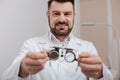 Cheerful friendly ophthalmologist holding eye test glasses