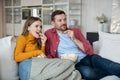 Friends couple watch TV funny movie comedy together sitting on couch at home enjoy eating popcorn. Royalty Free Stock Photo