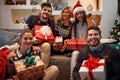 Cheerful friends holding boxes with Christmas gifts