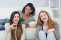 Cheerful friends with remote control and popcorn bowl at home Royalty Free Stock Photo