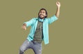 Cheerful funny indian man in headphones around his neck dancing and having fun on khaki background.