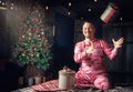 Cheerful funny man in pink sleepwear sitting on the bed and throws up Christmas present