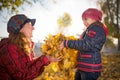 Cheerful and funny mother plays with yellow maple leaves Royalty Free Stock Photo