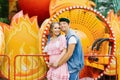 Funny young family waiting for their child relaxing in the amusement Park. They are happy and smiling. Dad-to-be holds hands on pr Royalty Free Stock Photo