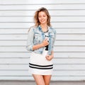 Cheerful funny young woman in american style near a white wooden house. Charming girl enjoys a warm sunny day Royalty Free Stock Photo