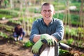 Cheerful gardener standing at smallholding during spring works