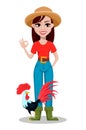 Cheerful gardener woman rancher showing ok sign and standing near rooster.