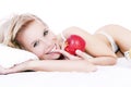 Bed of a beautiful blond woman holding apple.